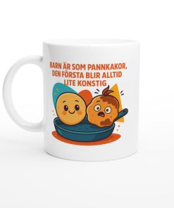 Vit mugg med tecknade pannkakor och texten “Barn är som pannkakor, den första blir alltid lite konstig” – rolig present med tryck till föräldrar