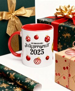 Rolig mugg med texten “Jag vann den här i julklappsspelet 2025” och röda julkulor – perfekt present med humor